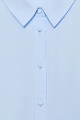 Camisa celeste de manga larga con cuello solapa y pliegues en los puños. Presenta cierre frontal con botones forrados al tono y bajo asimétrico.