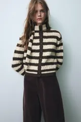 Chaqueta de punto a rayas horizontales en color marrón y beige, con cuello redondo, manga larga y cierre frontal con botones. Incluye una bufanda integrada del mismo tejido y diseño.