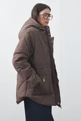 Campera puffer negra con diseño acolchado, capucha integrada y cierre frontal con botones a presión. Presenta puños elásticos y costuras decorativas en el frente.