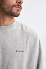 Sudadera de cuello redondo con efecto lavado, confeccionada en tejido de textura suave. Presenta un corte holgado con hombros caídos y puños y ruedo acanalados. Incluye una pequeña estampa minimalista en el pecho.