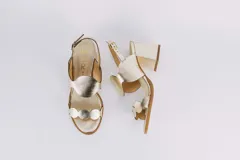 Sandalias doradas de cuero con taco cuadrado y diseño de ondas en el empeine y en la puntera. Cierre con hebilla en el tobillo.