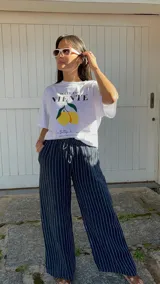 Pantalón de corte ancho y relajado, confeccionado en lino con diseño de rayas verticales. Presenta cintura elástica con cordón de ajuste y bolsillos laterales.