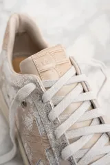 Zapatillas bajas de cuero color crema con detalles plateados y estrella lateral.