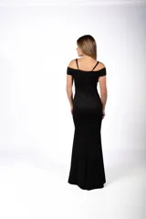 Vestido largo de fiesta color negro, con escote hombros descubiertos, tirantes finos y detalle de apliques brillantes en el escote. Presenta un corte ajustado al cuerpo con una abertura lateral profunda en la falda.