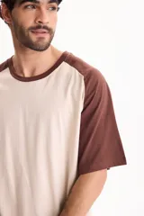 Remera oversize de manga corta raglán, color blanco con mangas y cuello en azul marino.