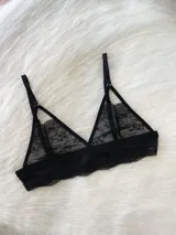 Bralette de encaje negro con diseño triangular, sin aros ni ganchos. Presenta breteles regulables y una banda inferior de encaje con terminación festoneada.