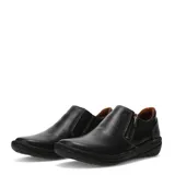 Zapatos casuales de cuero negro con cierre lateral metálico y costuras decorativas en contraste. Presentan una suela plana de goma con diseño ergonómico y forro interior en color marrón.