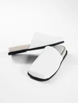 Zueco blanco con capellada con textura símil cocodrilo, plataforma baja y suela negra.