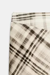 Falda midi de tiro alto con estampado de cuadros en tonos neutros. Presenta un diseño con abertura frontal en el bajo y cierre lateral con cremallera oculta.