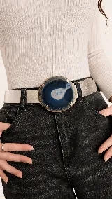 Cinturón de cuero metalizado plateado con una gran hebilla circular de piedra ágata natural en tonos azules y blancos con detalles metálicos dorados.