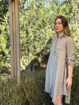 Vestido camisero color beige claro, de lino 100% natural, con botones de nácar, bolsillo delantero y mangas 3/4 con botón para recogerlas. Diseño asimétrico, más largo en la parte trasera.