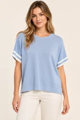 Remera de punto celeste, de manga corta con detalles de rayas blancas en los puños y cuello redondo, corte holgado.