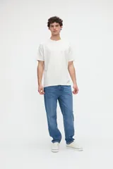 Remera de manga corta color blanco off-white, de calce clásico en tejido jersey de algodón. Presenta un gran diseño estampado en la espalda con un recuadro celeste que incluye las leyendas "WILD OCEAN" y "SALTY SOUL" junto con gráficos de olas y estrellas en tonos rosados y amarillos.