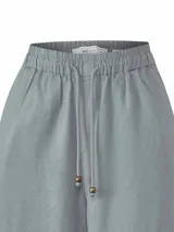 Pantalón de corte amplio y tiro alto, confeccionado en una mezcla de lino orgánico y viscosa. Presenta cintura elástica con cordón ajustable y detalles de encaje broderie tono sobre tono en los laterales y en el ruedo.