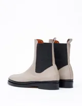 Bota Chelsea color hueso de cuero vacuno, con elástico lateral negro y suela de cuero.
