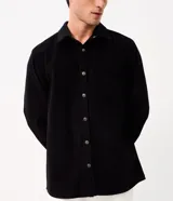 Camisa de terciopelo cotelé color negro, de corte clásico con cuello solapa, manga larga, cierre frontal de botones y un bolsillo aplicado en el pecho.