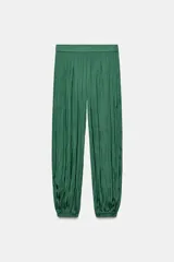 Pantalón de tiro medio confeccionado en tejido satinado verde, con diseño bombacho y bajos acabados en puño elástico. Cuenta con cierre lateral con cremallera oculta en costura.