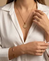 Dije de acero con baño de oro en forma octogonal, con grabado central del árbol de la vida.