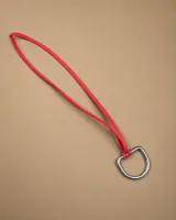 Gargantilla de cuero rojo con herraje metálico plateado en forma de D.