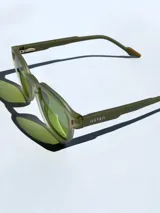 Lentes de sol con armazón de marco completo en color gris mate, con detalles decorativos en color rojo en las esquinas y patillas. Cuentan con cristales oscuros polarizados con protección UV 400.