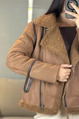 Campera tipo gamulán de color crema con interior y cuello de corderito sintético. Presenta cierre frontal cruzado, bolsillos laterales con cierre y detalles de costuras en contraste color marrón oscuro.