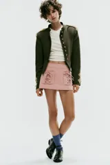 Falda mini de tiro bajo color rosado con estampado de rayas verticales. Presenta dos bolsillos de parche en el frente con detalles de cordones cruzados ajustables y cierre lateral con cremallera oculta.