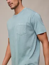 Remera básica de cuello redondo con bolsillo frontal, confeccionada en algodón con efecto de lavado gastado.