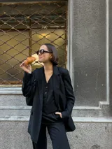 Blazer negro de lana con rayas verticales finas, corte clásico, solapas de muesca y cierre con botones.