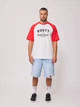 Remera blanca con mangas raglán negras y estampado frontal con el logo de Rusty en azul.