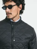 Campera capitoneada de color azul oscuro, con cierre frontal de metal y botones a presión. Presenta bolsillos laterales y en el pecho con cierres metálicos.