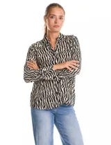 Camisa de manga larga con cuello solapa y cierre frontal de botones. Presenta un diseño estampado con patrón de cebra en tonos blanco y negro, puños abotonados y ruedo redondeado.