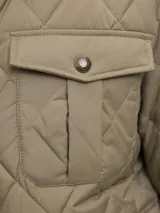 Campera acolchada de diseño matelasse en color tostado, con cuello camisero en pana marrón, cierre frontal con broches a presión, bolsillos frontales con solapa y puños ajustables.