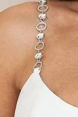 Vestido largo blanco de corte recto y elegante, con tirantes finos decorados con pedrería brillante y tajo lateral profundo en la falda.