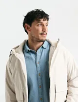Campera impermeable negra con capucha, cierre frontal, bolsillos frontales con tapa y puños elásticos.