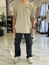 Remera oversize color beige, con mangas corta y gran estampado gráfico en la espalda con texto en negro.