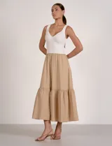 Vestido largo combinado de la marca Elan, con torso en tejido de punto acanalado blanco de escote en V y breteles anchos, y falda midi fluida en color beige con volante fruncido en el ruedo.