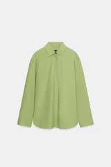 Camisa oversize verde de popelina de algodón, con cuello solapa, manga larga y cierre frontal con botones ocultos bajo solapa.