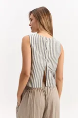 Blusa crop sin mangas de cuello redondo, con diseño a rayas en tonos azul y blanco, y espalda abierta con cierre de botones.