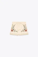 Bermuda color crudo confeccionada en algodón y lino, con tiro medio, cintura elástica ajustable con cordones y bordado floral a contraste en los laterales.
