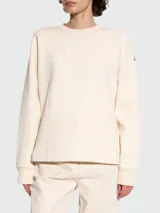 Buzo de algodón color crema, de cuello redondo y manga larga, con logo bordado en el frente.