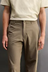 Pantalón técnico de corte regular fit en color marrón, confeccionado en tejido elástico y compacto. Cuenta con cintura ajustable con cordón interior, bolsillos frontales, bolsillo trasero con cierre oculto y bolsillo lateral con cierre en la pernera. El bajo es ajustable mediante botones a presión.