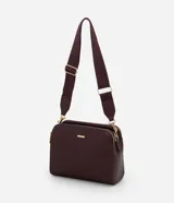 Cartera bandolera de tamaño mediano en cuero sintético color bordó, con formato rectangular y múltiples compartimentos con cierre de cremallera. Incluye correa de hombro ajustable en grosgrain y herrajes metálicos dorados.