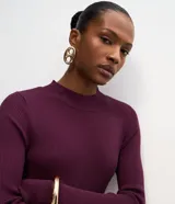 Vestido midi de punto acanalado color bordó, con cuello redondo y mangas largas. Presenta un diseño ajustado en el torso que se extiende hacia una falda con caída fluida.