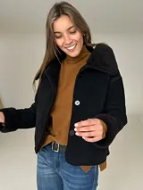 Campera tipo gamulán color negro con interior de corderito sintético, cuello solapa y cierre frontal con botones. Diseño corto y holgado.