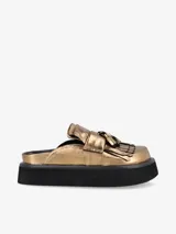 Zueco dorado con plataforma negra y detalle de flecos en la parte delantera.