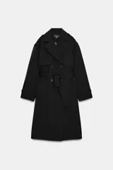 Trench largo de color negro con cuello de solapa, cierre frontal cruzado con botones y cinturón ajustable a tono. Presenta mangas largas con trabillas en los puños, bolsillos delanteros de vivo y abertura en la espalda.