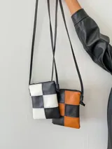 Monedero pequeño con correa larga, con diseño de tablero de ajedrez en blanco y negro.