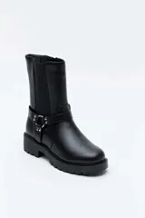 Bota alta color negro, con suela track y taco cuadrado. Presenta una tira con tachas y una argolla metálica decorativa alrededor del tobillo, además de inserciones elásticas laterales.