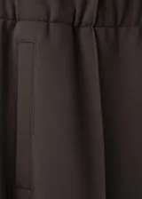 Pantalón deportivo negro con líneas blancas laterales, tiro alto y diseño recto.