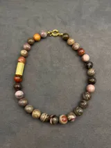 Collar de piedras naturales en tonos tierra, con detalle de tubo dorado en un lateral y cierre marinero dorado.